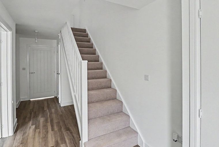 A hallway with a staircase, doors, and wood-effect flooring.