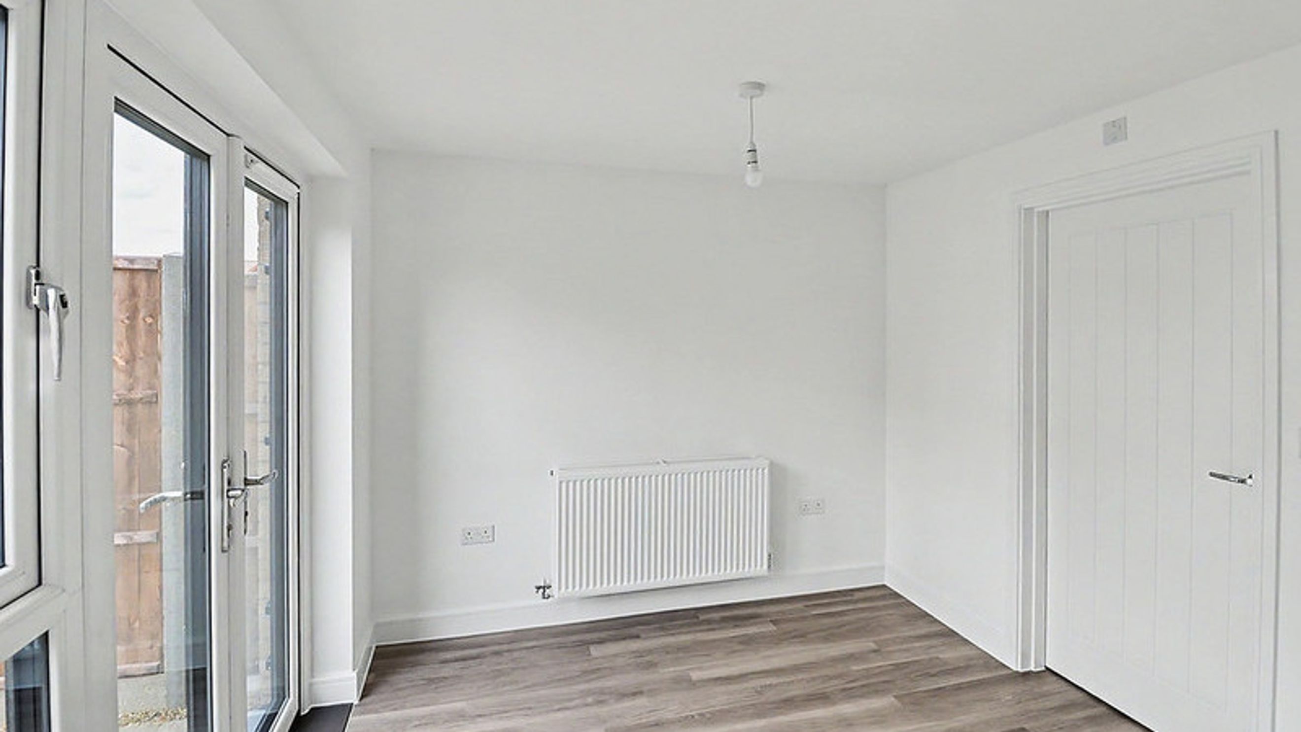 A room with double doors, a radiator, and a white door.