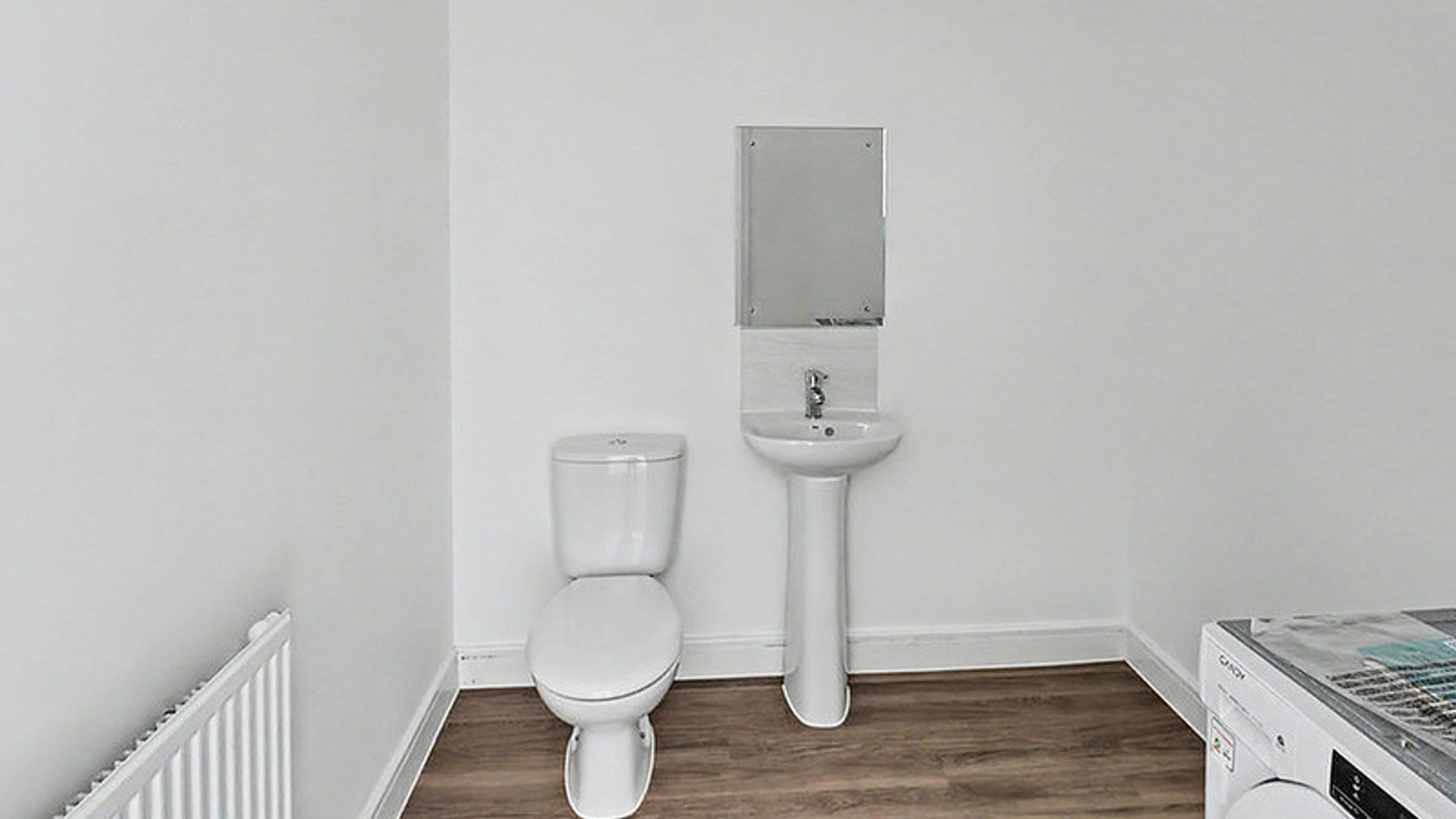 A bathroom with a toilet, sink, mirror, and washing machine.