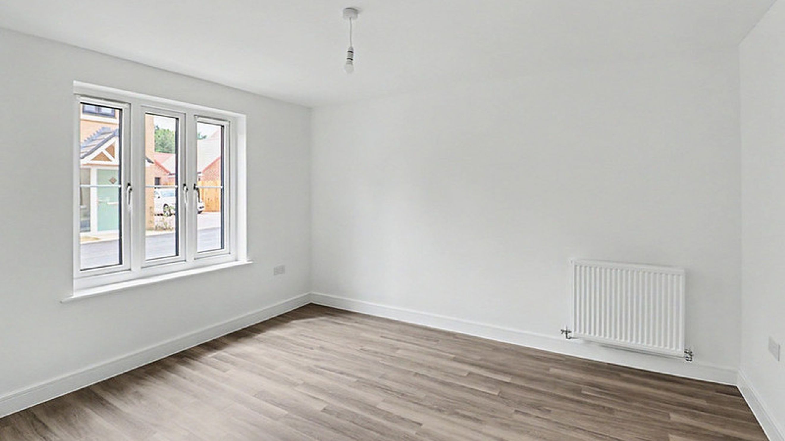 A room with a window, a radiator, and a light fixture.