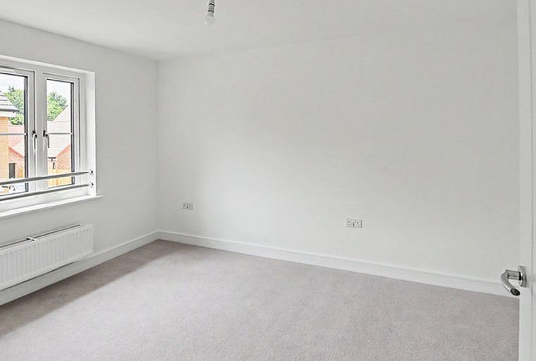 A bedroom with a window, radiator, and a door.