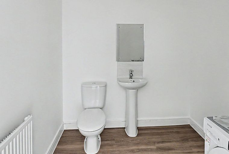 A bathroom with a toilet, sink, mirror, and washing machine.