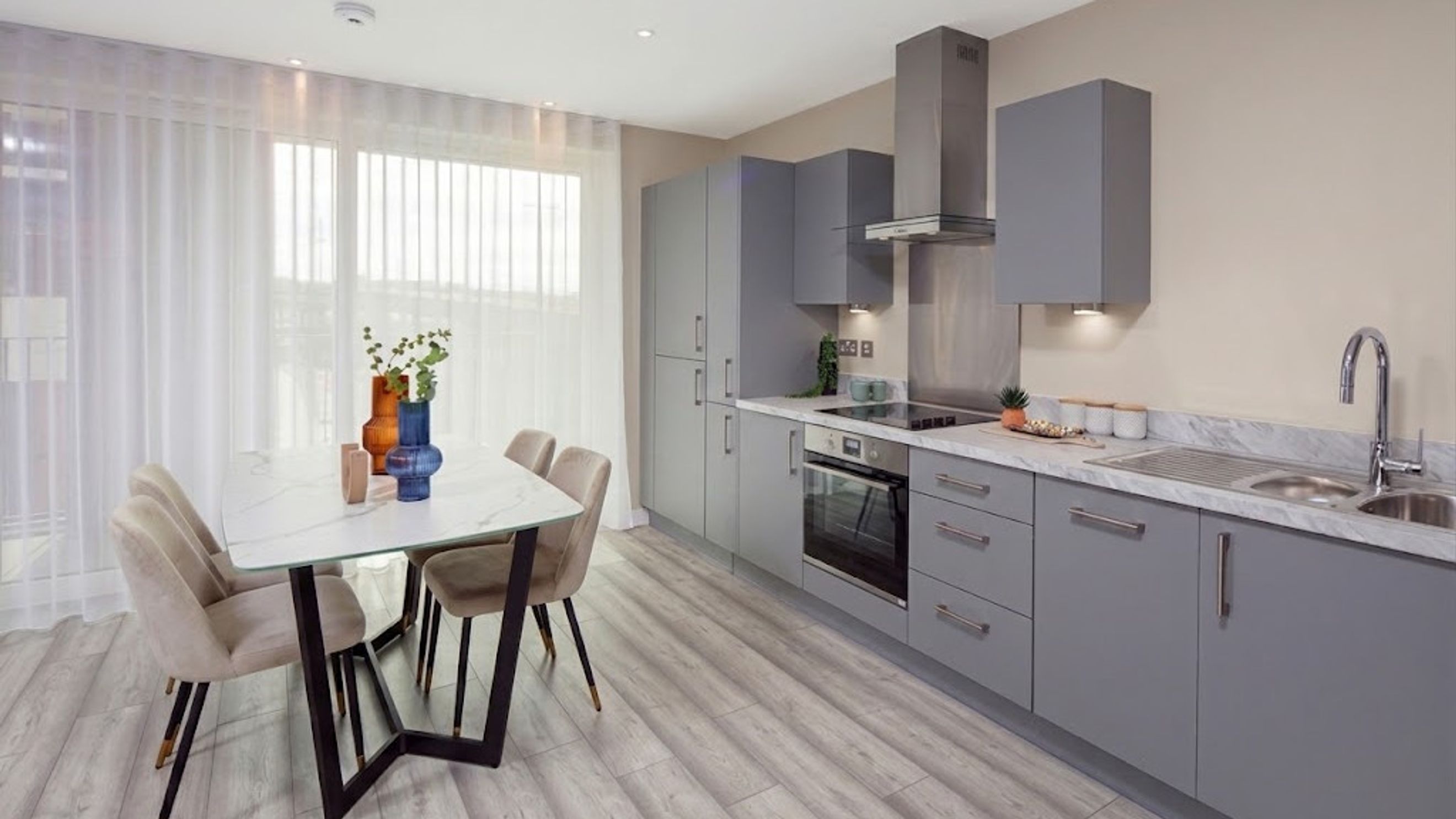 A kitchen and dining area with grey cabinets, a marble countertop, and a dining table with chairs.