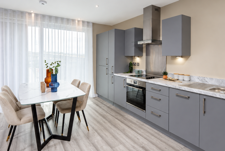 A modern kitchen and dining area with grey cabinets, a marble countertop, and a dining table with chairs.