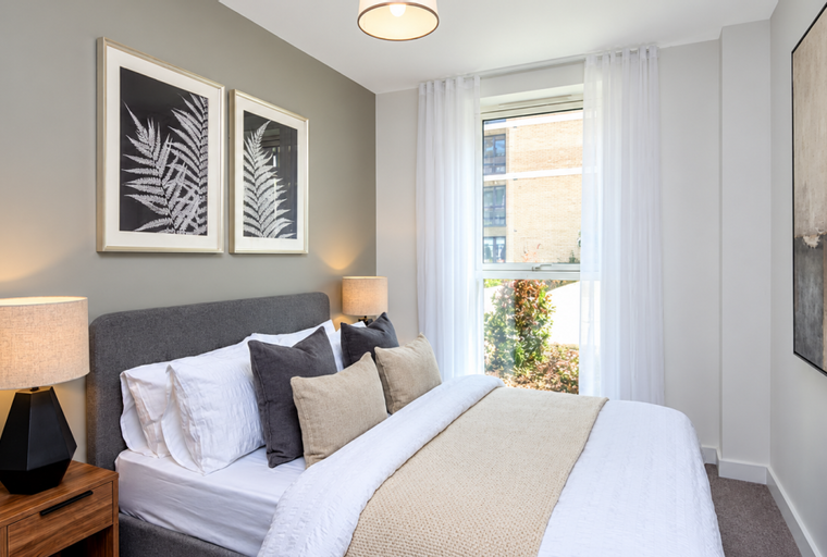 A bedroom with a bed, bedside tables, and a window.