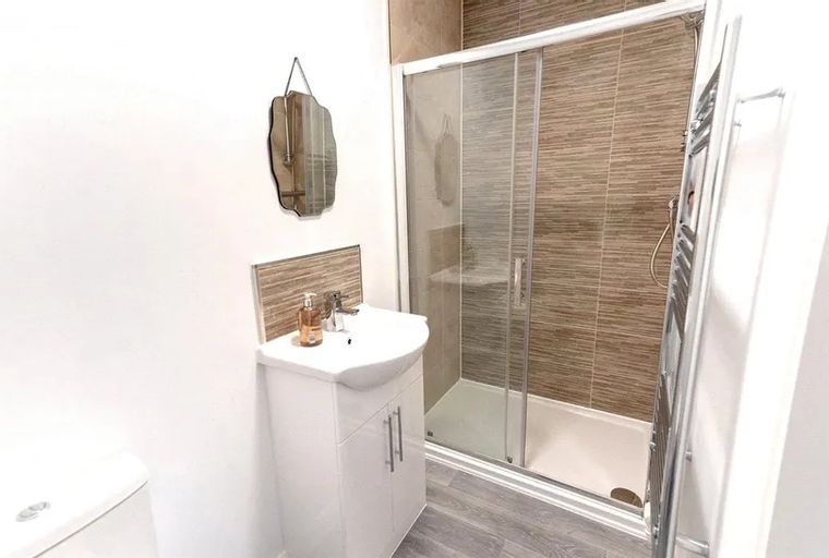 A bathroom with a sink, shower, and towel warmer.