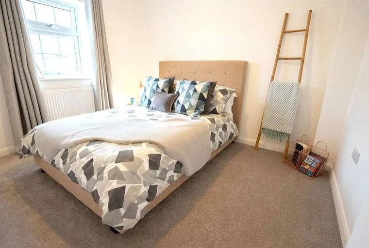A bedroom with a bed, pillows, and a ladder shelf.