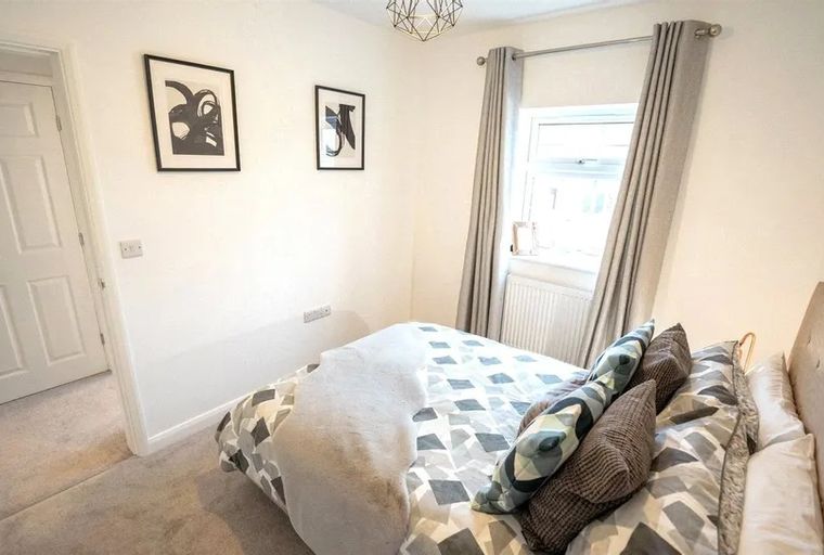 A bedroom with a bed, pillows, a window, and a door.