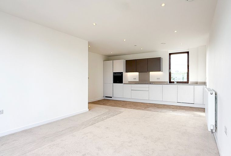 A modern, unfurnished apartment with a kitchen and living area.