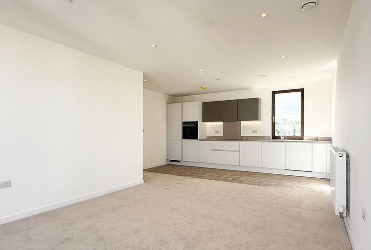 A modern apartment living area with a kitchen and a large window.