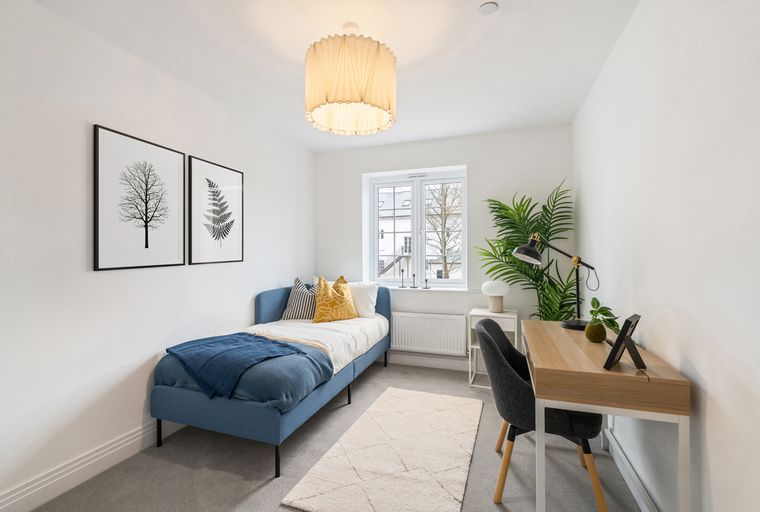 A bedroom with a blue daybed, a desk, and two framed art prints on the wall.
