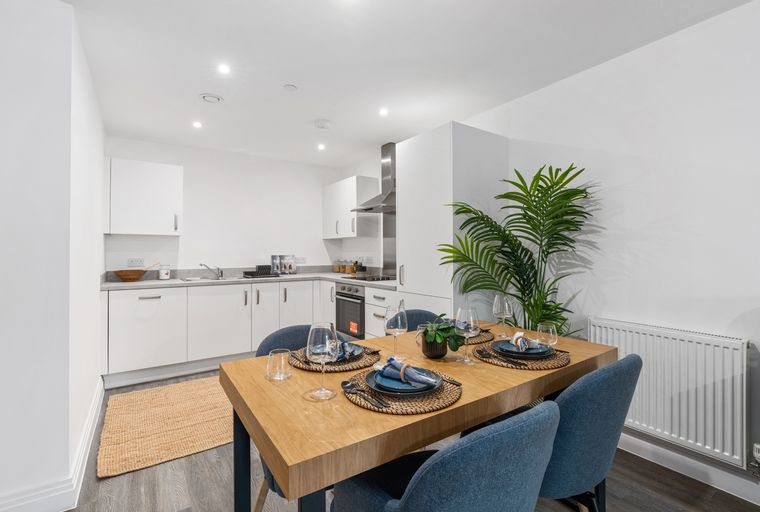 A dining area with a wooden table and chairs next to a kitchen.