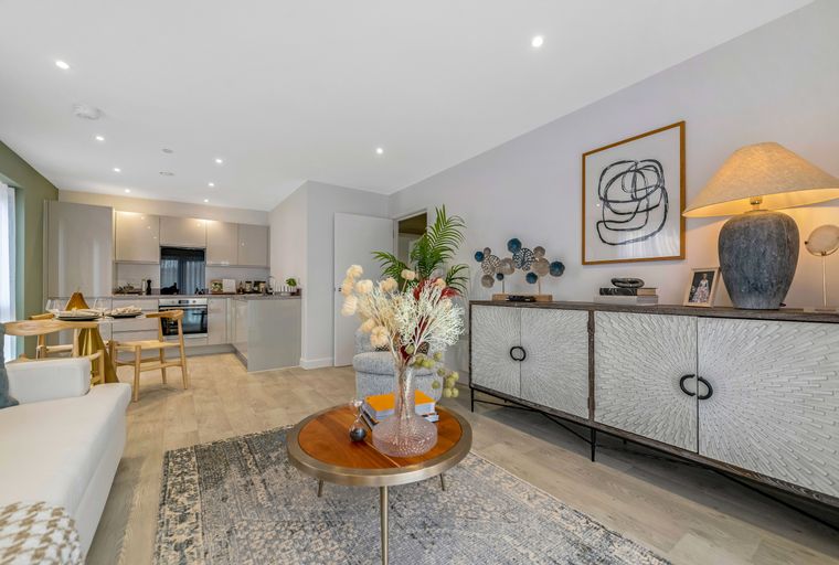 A living room and kitchen area with a sofa, coffee table, dining table, and kitchen cabinets.