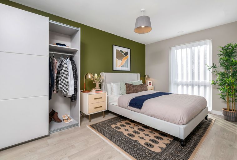 A bedroom with a bed, a wardrobe, a bedside table, and a rug.