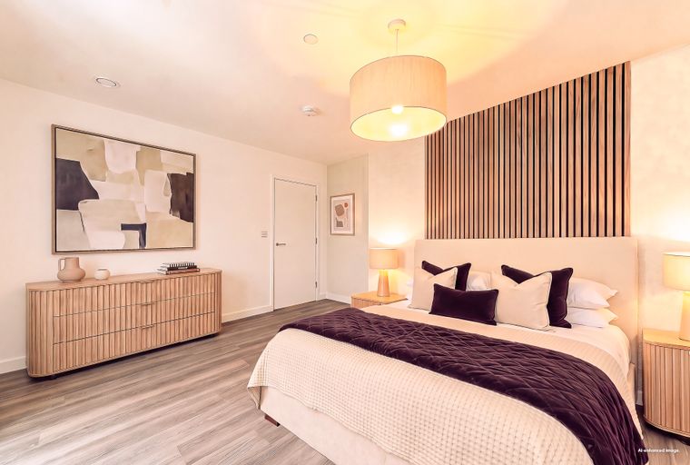 A bedroom with a bed, nightstands, a dresser, and artwork.