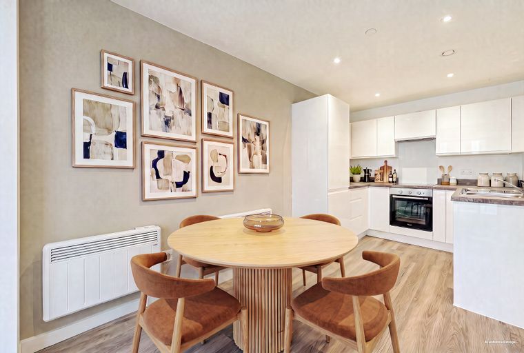 A dining area with a round wooden table and chairs next to a modern kitchen.