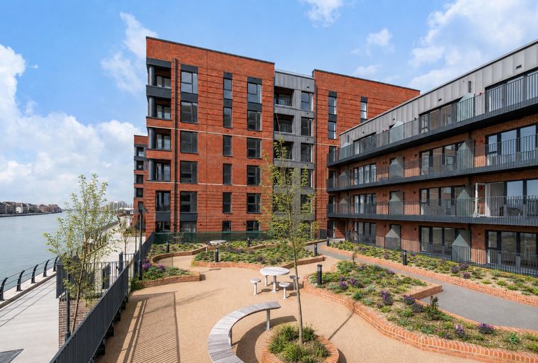 A courtyard with modern apartment buildings and a river in the background.