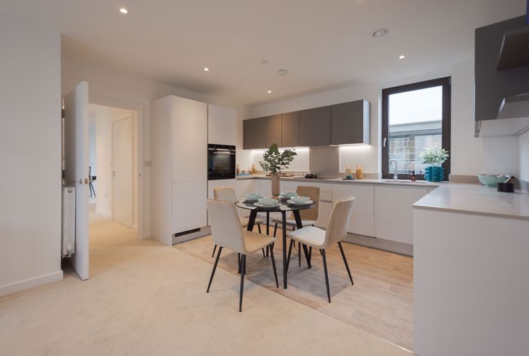 A kitchen and dining area with a round table, four chairs, and modern cabinetry.