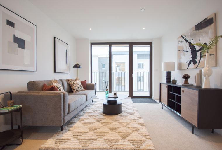 A living room with a sofa, coffee table, rug, and a sideboard.