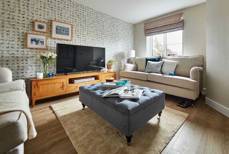 A living room with a sofa, ottoman, television, and media console.