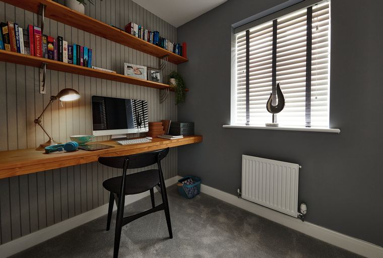 A home office with a wooden desk, computer, chair, and bookshelves.