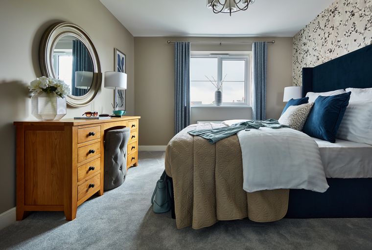 A bedroom with a bed, dresser, and a round mirror.