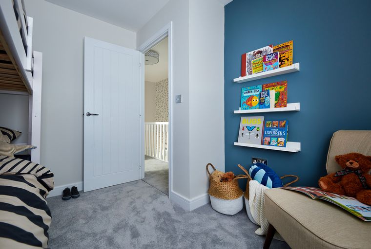 A children's bedroom with books on shelves, a teddy bear, and a bunk bed.