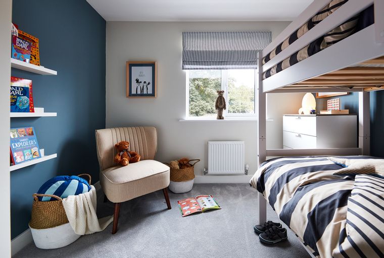 A children's bedroom with a bunk bed, armchair, and bookshelves.