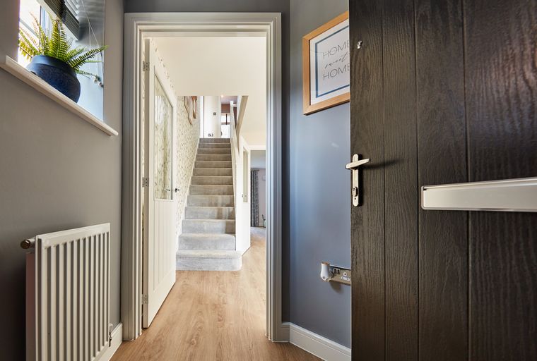 A hallway with a front door, radiator, and staircase.
