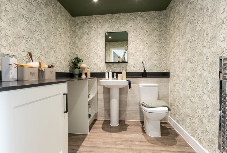 A bathroom with a toilet, sink, and dog-themed wallpaper.