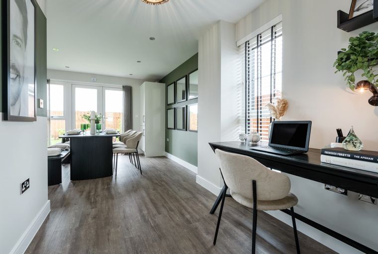 A dining area and a desk with a laptop.
