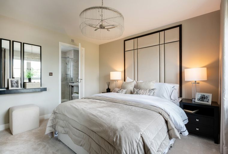 A bedroom with a bed, bedside tables, lamps, a chandelier, and an adjoining bathroom.