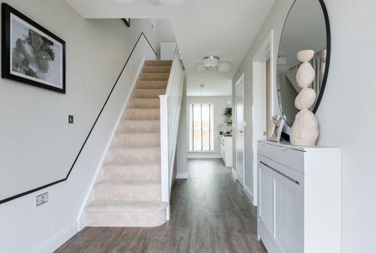 A hallway with a carpeted staircase, a large mirror, and a radiator cover.