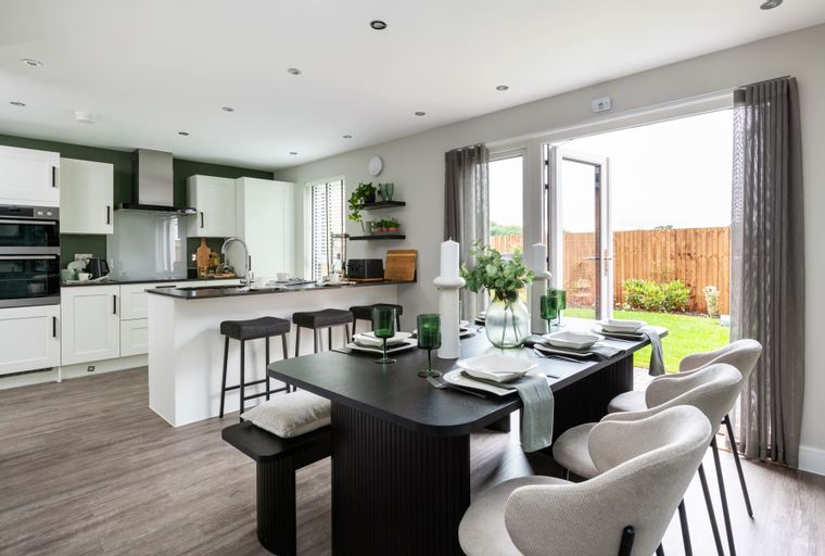 A dining area and kitchen with a breakfast bar and a view of a backyard through glass doors.