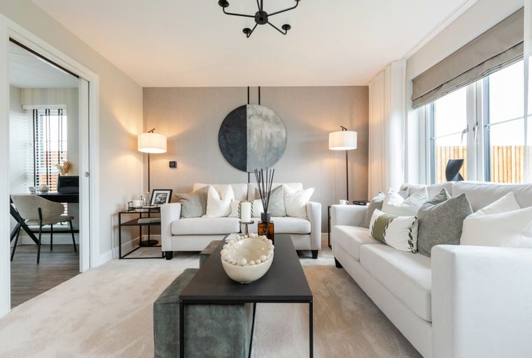 A living room with two white sofas, floor lamps, and a circular wall art.
