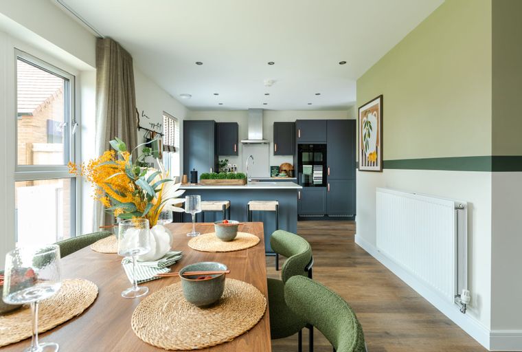 A dining area and kitchen with dark cabinets, an island, and a wooden table set for a meal.