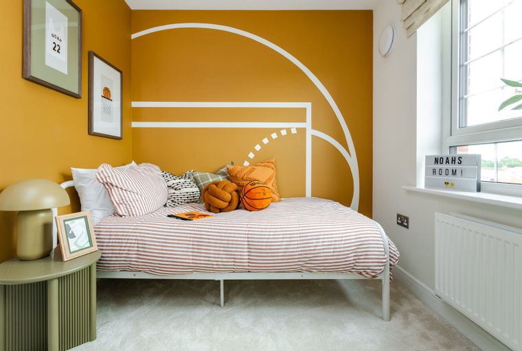 A bedroom with a bed, pillows, a basketball, and wall art.