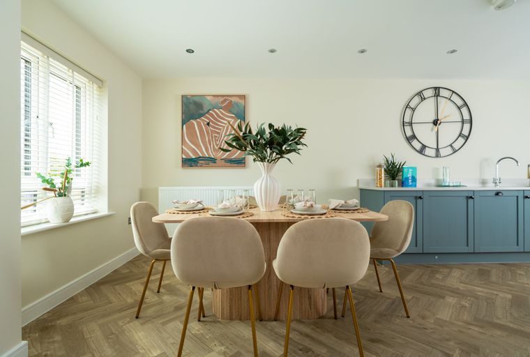 A dining room with a table, chairs, and a large clock on the wall.