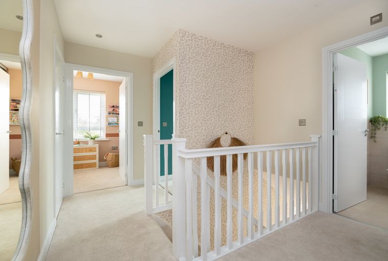 A hallway with a banister and doors leading to rooms.