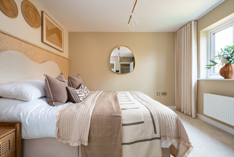 A bedroom with a bed, pillows, blankets, and wall decor.