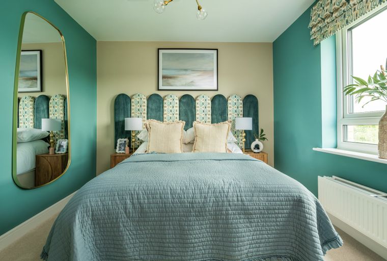 A bedroom with a bed, headboard, lamps, and a mirror.