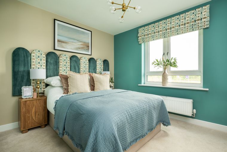 A bedroom with a bed, headboard, pillows, and a window.