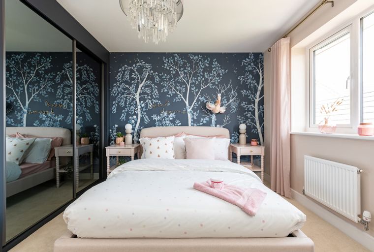A bedroom with a bed, bedside tables, and a mirrored wardrobe.