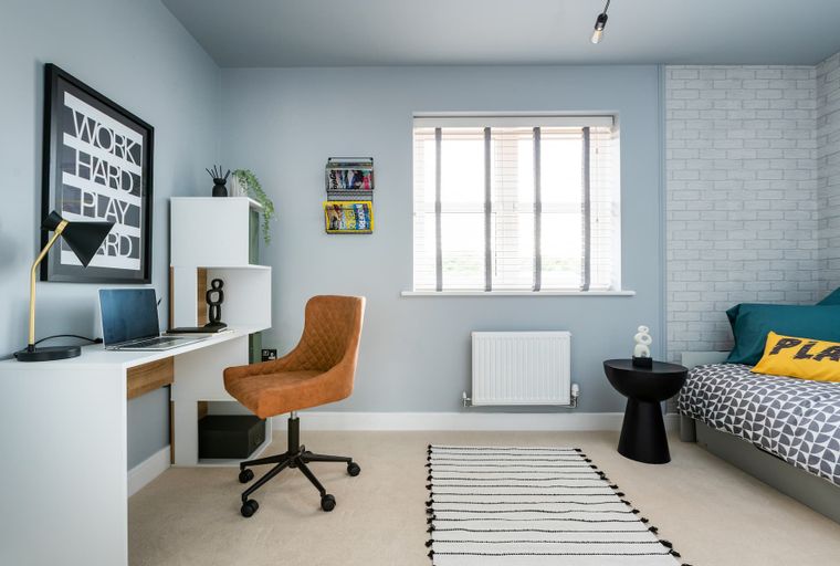 A bedroom with a desk, chair, bed, and window.