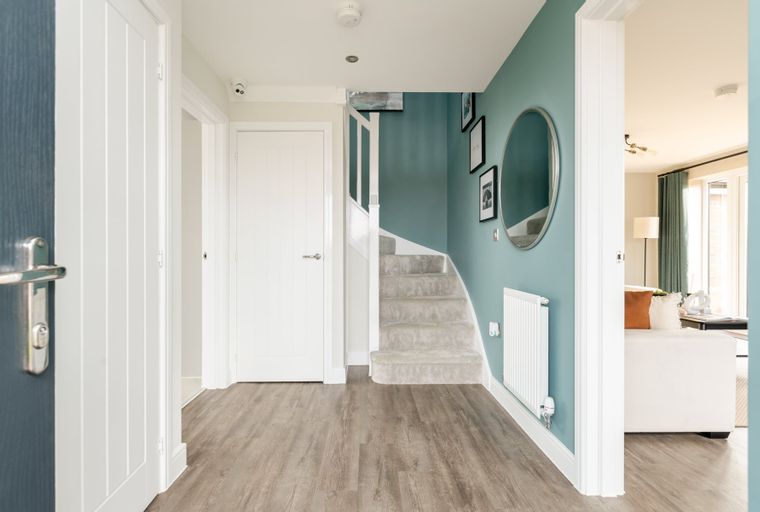 A hallway with a staircase, doors, and a teal accent wall.