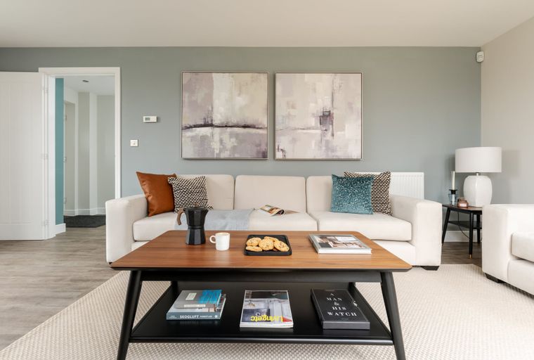 A living room with a cream sofa, coffee table, and abstract art.
