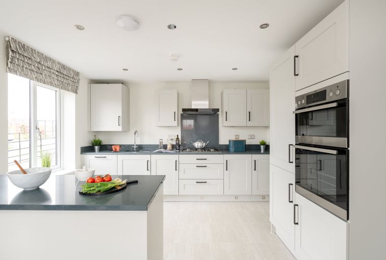 A modern kitchen with white cabinets, a dark countertop, and stainless steel appliances.