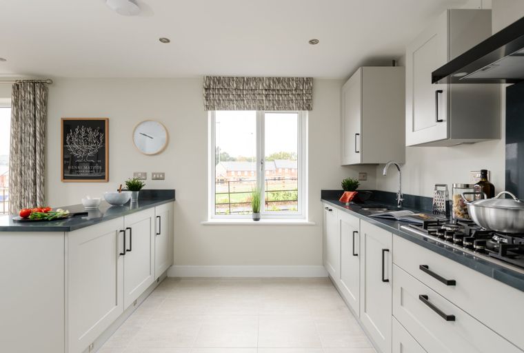 A U-shaped kitchen with white cabinets, dark countertops, and a window.