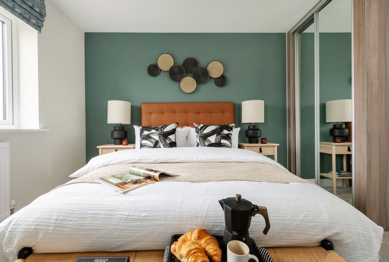 A bedroom with a bed, bedside tables, lamps, and a mirrored wardrobe.