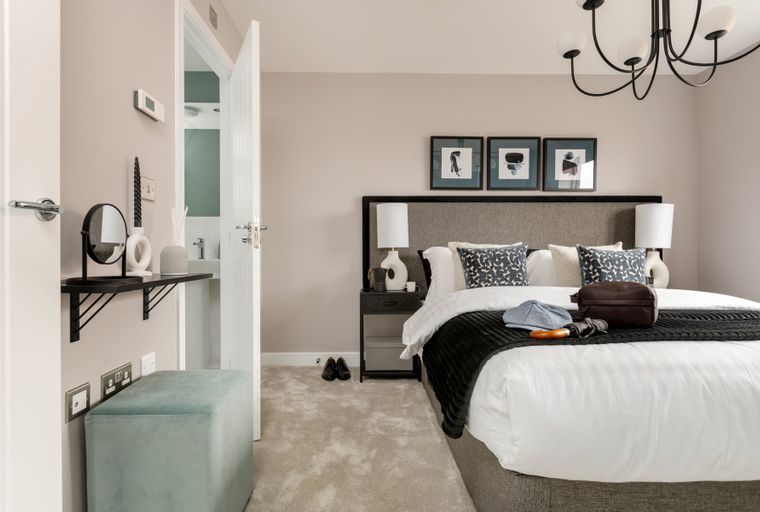A bedroom with a bed, bedside table, and a vanity area.